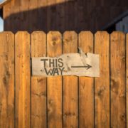 Brown wooden fence with sign that reads "This Way" with an arrow to online leadership training benefits.